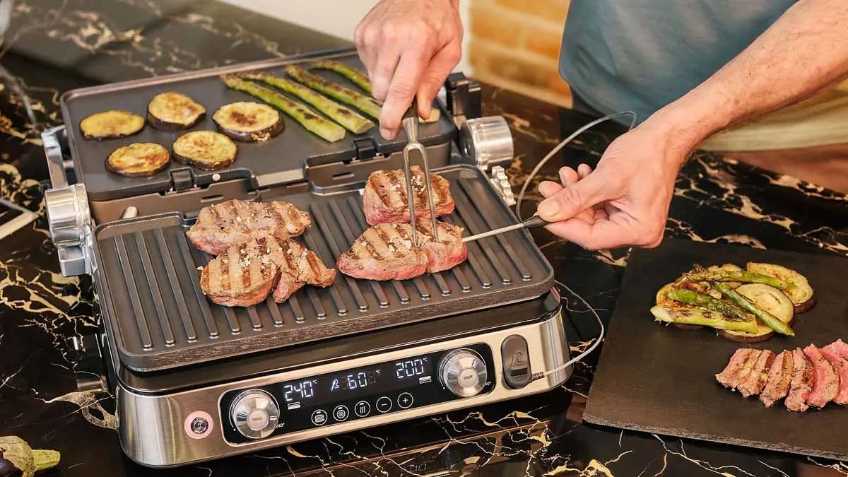 Ein Mann misst die Kerntemperatur von Steaks auf dem Braun Kontaktgrill MultiGrill 9 Pro.