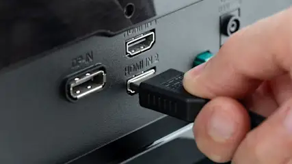 Eine Person verbindet einen HDMI-Stecker mit einem HDMI-Anschluss.