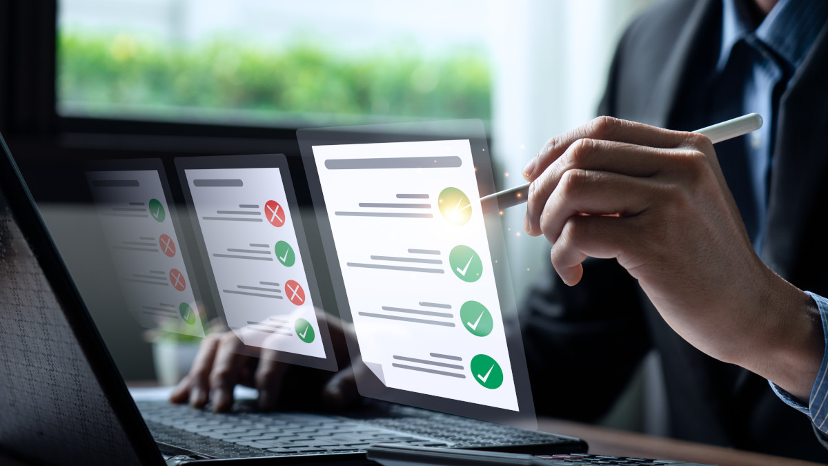 Geschäftsmann mit Laptop bearbeitet eine digitale Checkliste.
