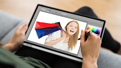 Eine Person benutzt einen Stift auf einem Laptop, um ein digitales Bild einer Frau mit Einkaufstüten zu bearbeiten.