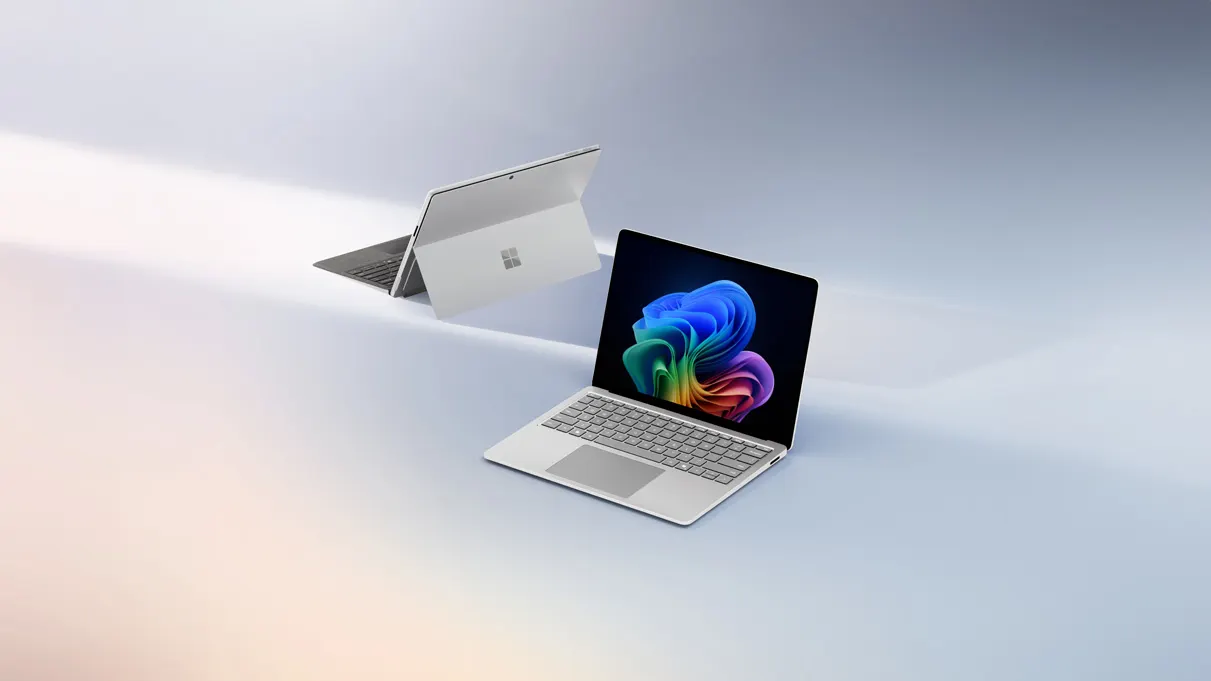 Ein silberner Laptop mit farbigem Bildschirm steht auf einem hellen Untergrund. Im Hintergrund ist ein zweiter Laptop sichtbar.