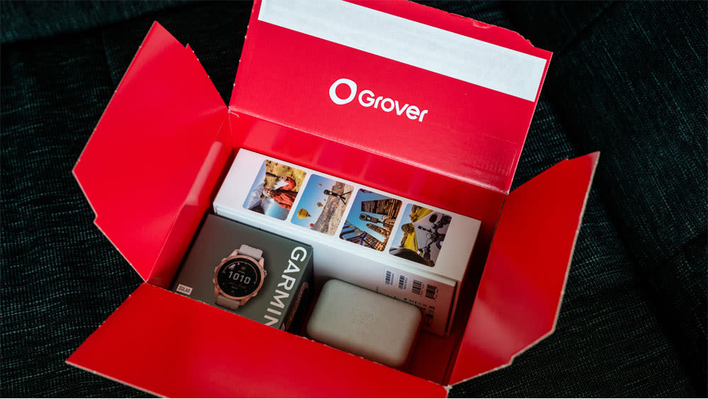 Insta360-Kamera, Garmin Fenix 7S Solar und Sony WF-1000 XM4 liegen originalverpackt in einem Grover-Karton.
