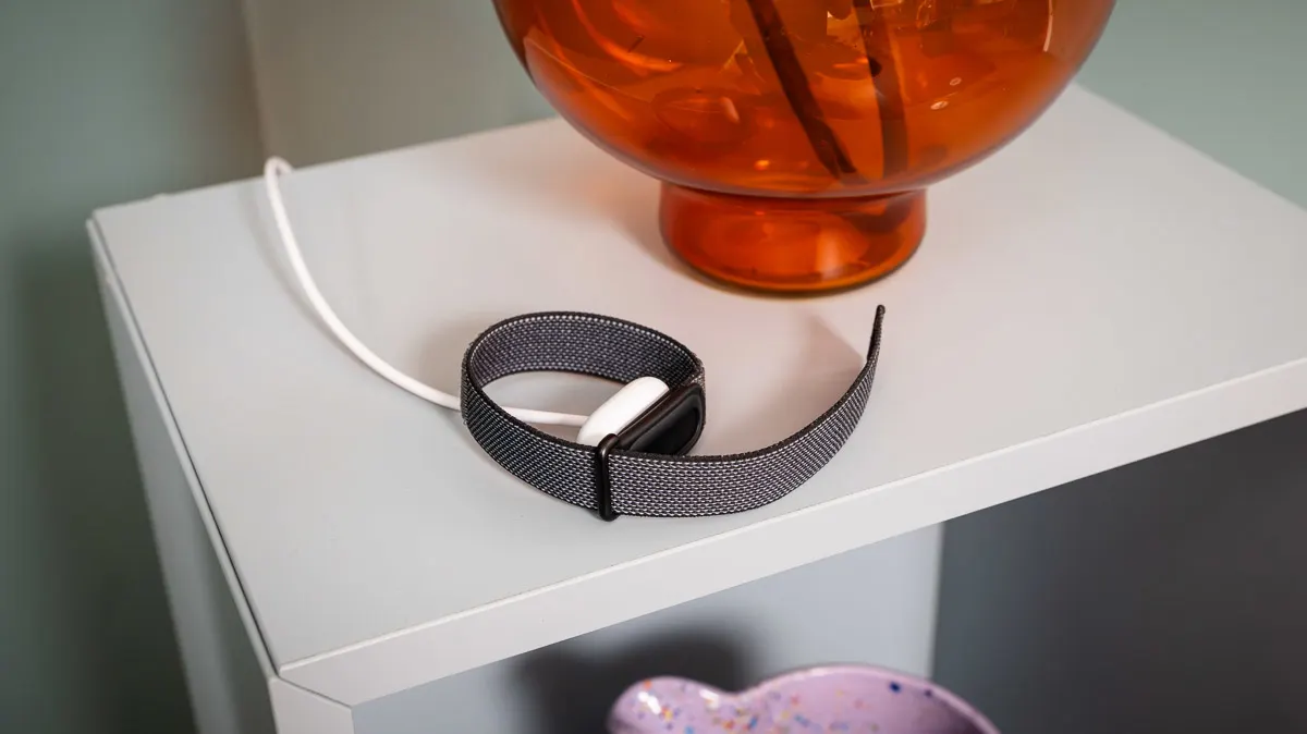 Das Fitbit Air liegt auf einem Regal und ist ans Ladekabel angeschlossen.