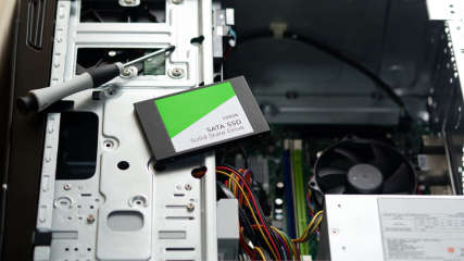 Eine 2,5-Zoll-SSD liegt für den Einbau auf einem offenen Desktop-PC bereit.