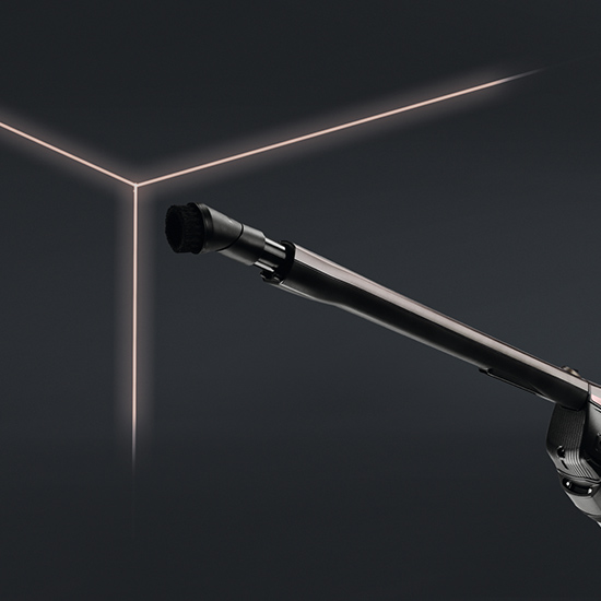 Eine schwarze, rohrartige Staubsaugerverlängerung ragt vor einem dunklen Hintergrund mit leuchtenden Linien hervor.