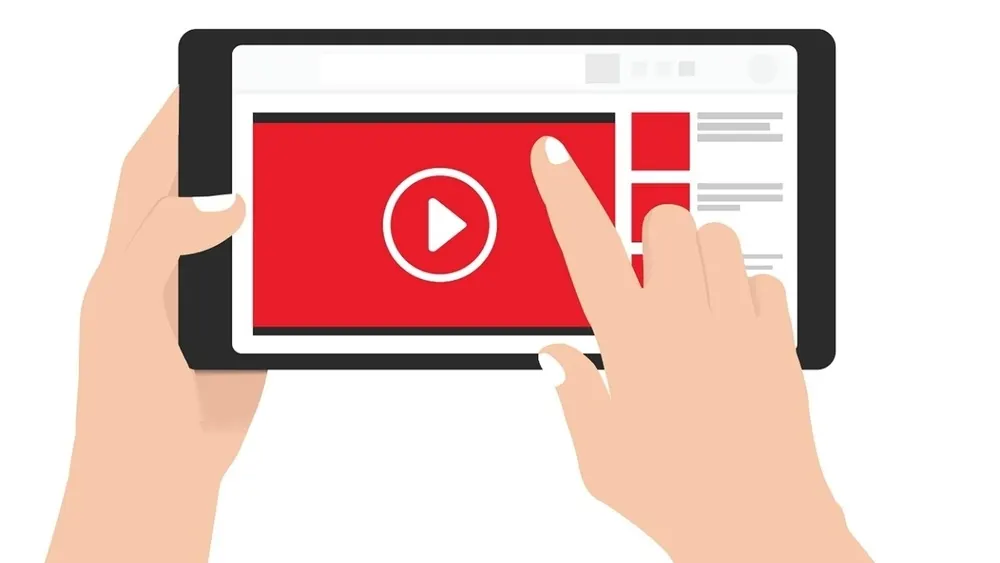 Eine Person hält ein schwarzes Tablet mit rotem Wiedergabebildschirm. Ein Finger berührt den Bildschirm vor einem weißen Hintergrund.