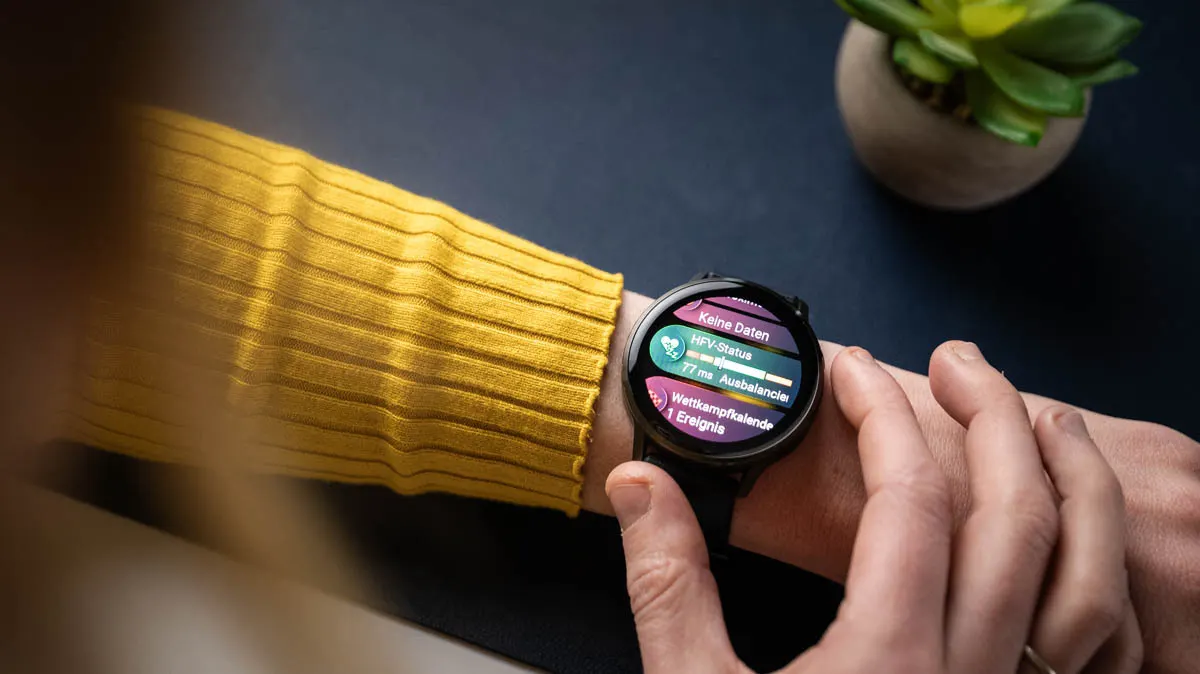 Franzi schaut sich die Übersichten auf der Garmin Venu 4 an, zu sehen sind HFV-Status (Herzfrequenzvariabilität) und Wettkampfkalender.