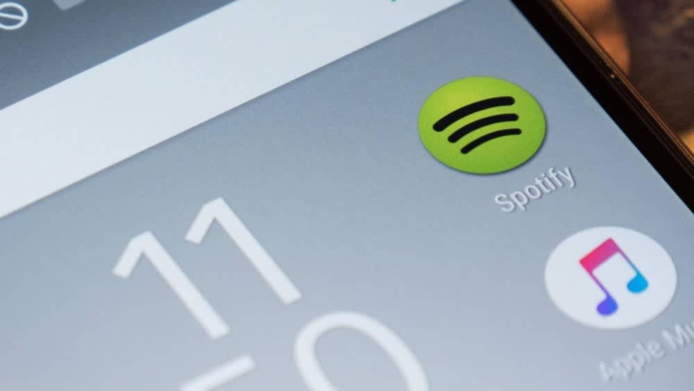 Ein Smartphone auf dem Spotify und Apple Music auf dem Display erscheinen.