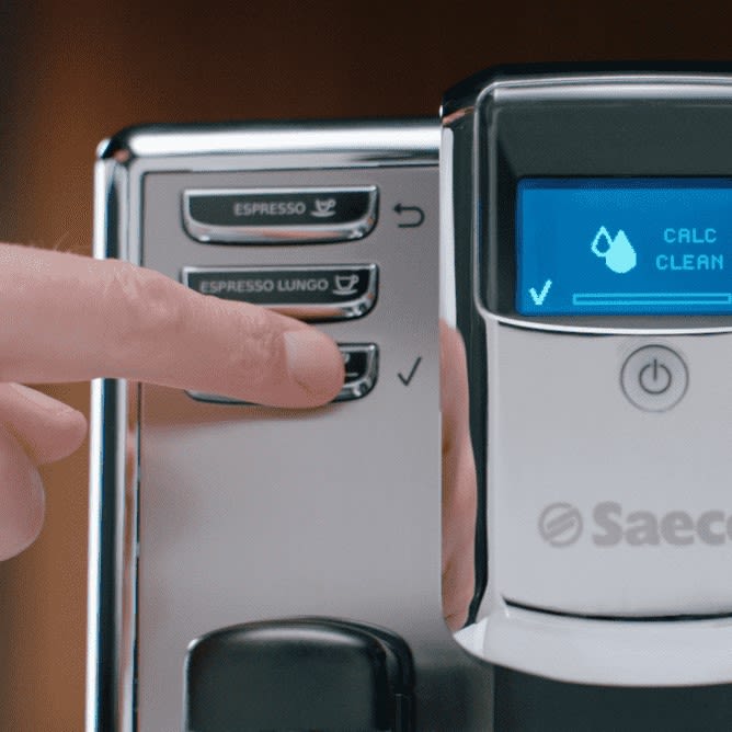 Ein Finger drückt auf eine Bedientaste eines Saeco Kaffeevollautomaten.