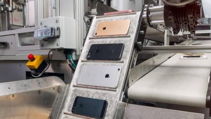 Unterschiedliche iPhones liegen auf einem Laufband in einer Fabrik.
