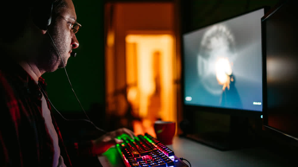 Ein Mann spielt mit einer bunt beleuchteten Gaming-Tastatur.