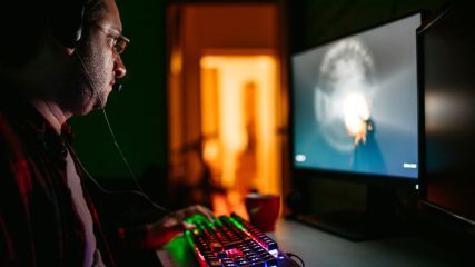 Ein Mann spielt mit einer bunt beleuchteten Gaming-Tastatur.
