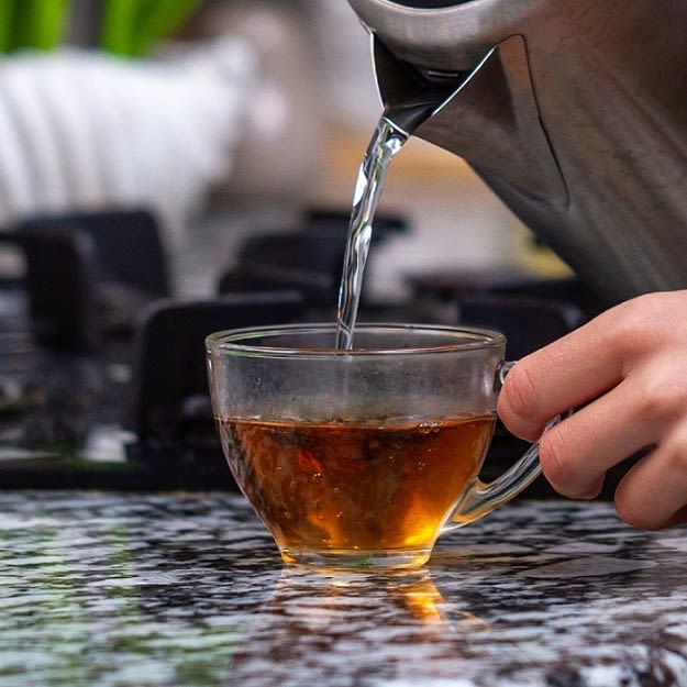 Eine Person gießt einen Tee mit heißem Wasser aus dem WMF 04.1302.0012 Stelio Wasserkocher auf.