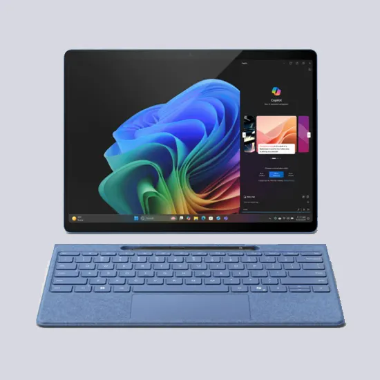 Ein Tablet-Computer mit angebrachter blauer Tastatur liegt vor einem grauen Hintergrund. Das Display zeigt ein farbenfrohes abstraktes Muster.