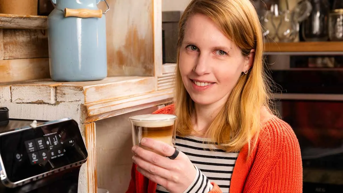 Franzi hält einen Latte Macchiato in der linken Hand und trägt den Ultrahuman Ring Air am linken Zeigefinger.