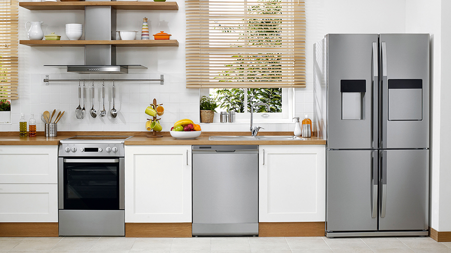 Eine Küche mit weißen Schränken, einer Spüle unter einem Fenster mit Jalousien und einem silbernen Kühlschrank.