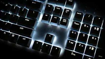 Nahaufnahme einer Computertastatur mit Hintergrundbeleuchtung unter schwachem Licht. Tasten mit Beschriftungen wie "Enter", "Shift" und Zahlen sind sichtbar.