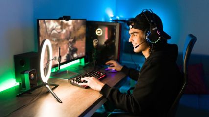 Ein junger Mann mit Kopfhörern sitzt vor einem Gaming PC