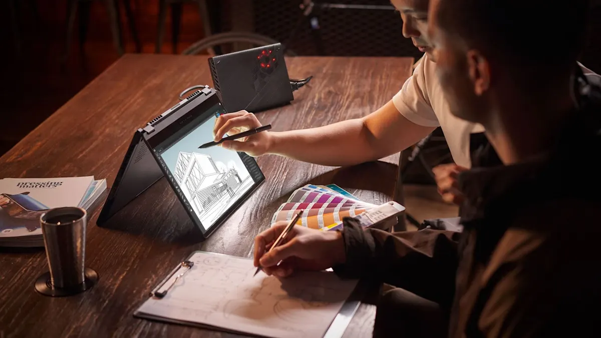 Zwei Personen arbeiten an einem Tisch mit Laptop, Stiften, Farbfeldern und Papier. Ein Gebäudeentwurf ist auf dem Laptop-Bildschirm zu sehen.