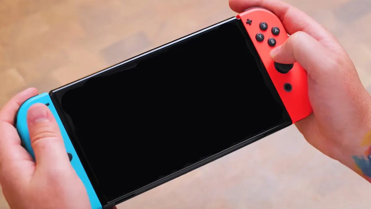 Zwei Hände halten eine Nintendo Switch in der Hand. Das Display ist schwarz.