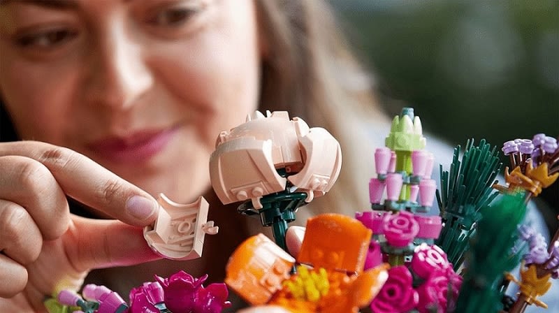 Eine Frau arrangiert das LEGO 10280 Blumenstrauß Spielset, Mehrfarbig