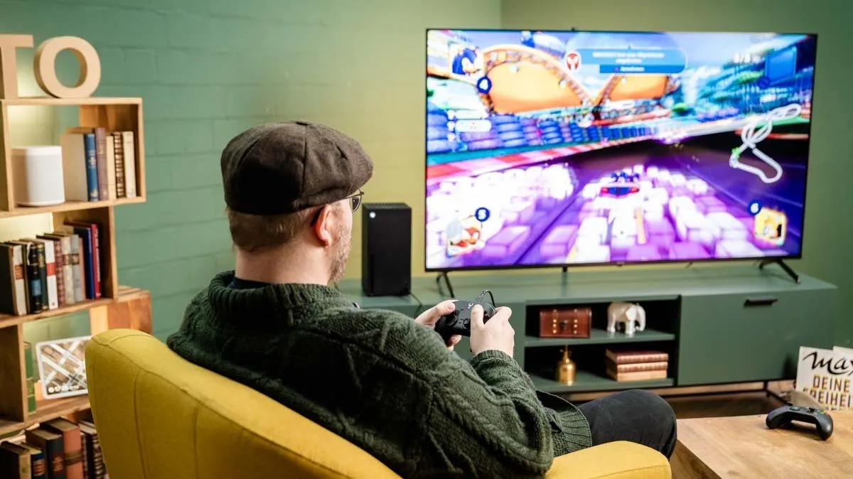 Andreas sitzt vor einem großen Fernseher und spielt ein Sonic-Rennspiel an der Xbox Series X.