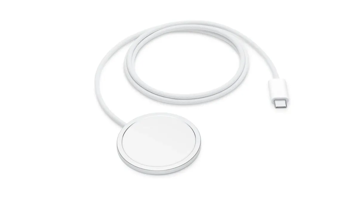 Das Apple MagSafe-Ladegerät liegt zusammengerollt auf einem weißen Untergrund.