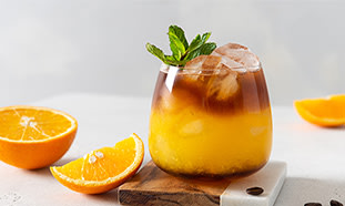 In einem Glas ist ein Getränk eingeschenkt, das unten orange ist und oben braun. Es ist eine Bumble Coffee, also der Mix aus Espresso und Orangen-Saft.