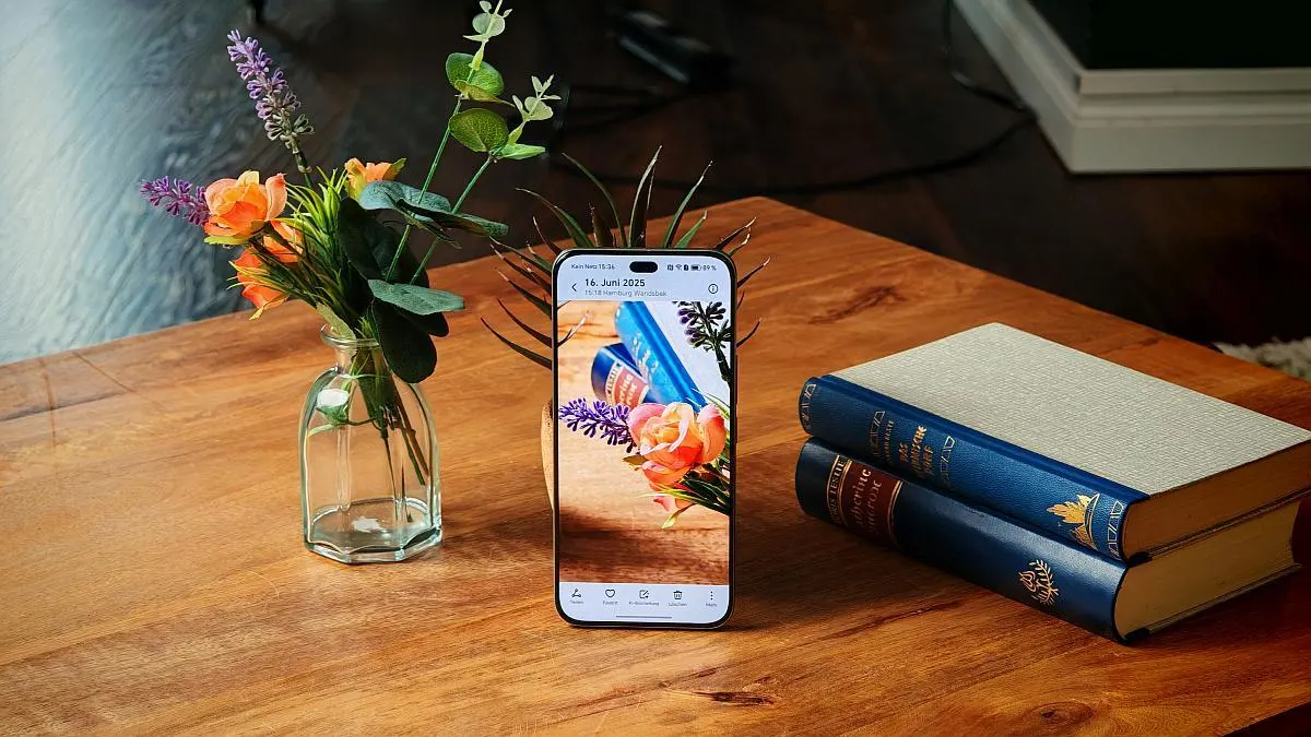 Das Honor 400 Pro lehnt auf einem Tisch an einer Blumenvase neben Büchern und Blumen in einer anderen Vase.