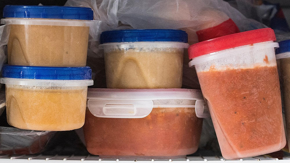 Ein Tiefkühlfach ist mit eingefrorenen Suppen in Frischhaltedosen vollgestellt.