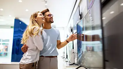 Eine Frau und ein Mann sehen sich im Fachhandel Fernseher an.