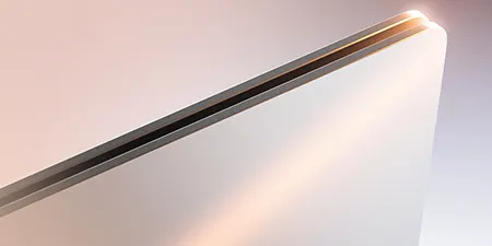 Nahaufnahme eines silbernen Laptops mit schwarzem Scharnier auf hellem Hintergrund, der einen Lichtreflex erzeugt.