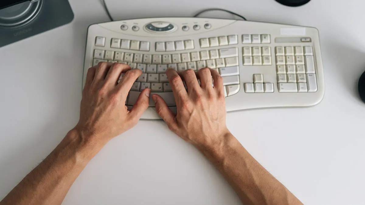 Zwei männliche Hände tippen auf einer ergonomischen Tastatur.