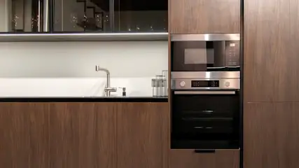 Eine Küche mit braunen Holzfronten und einer Einbaumikrowelle sowie einem Einbauofen.