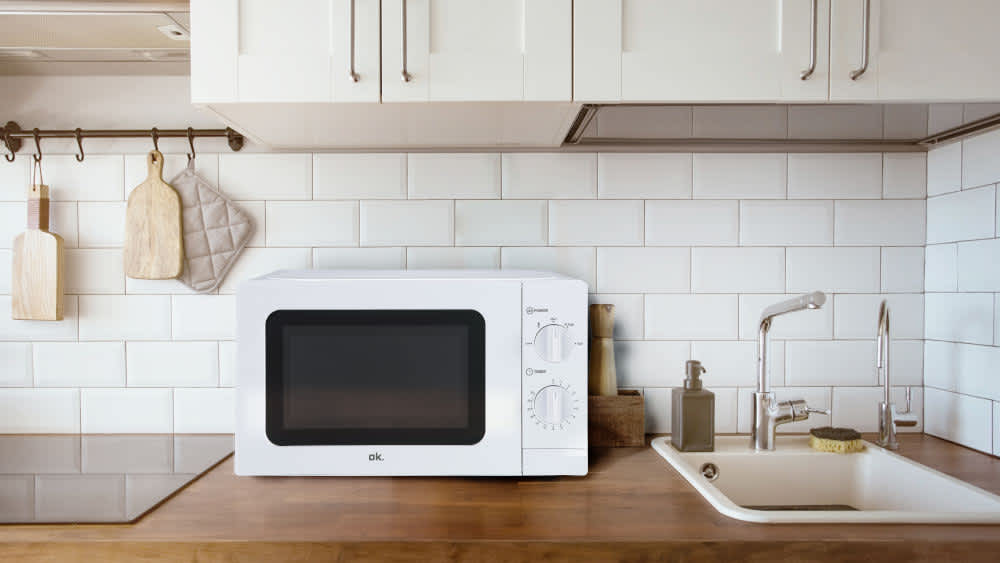 Die Mikrowelle OMW 2022 W von ok. auf einer Arbeitsplatte in einer weißen Küche.