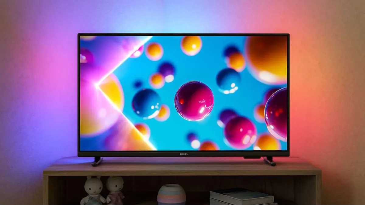 Der 32-Zoll-Fernseher Philips 32PFS6900/12 steht auf einem Sideboard. An der Wand dahinter reflektiert das Ambilight.