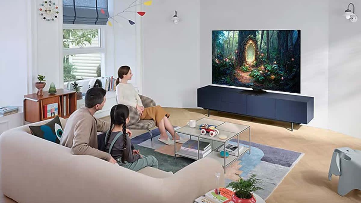 Eine Familie in einem Wohnzimmer sieht fern auf einem Samsung QN85C.