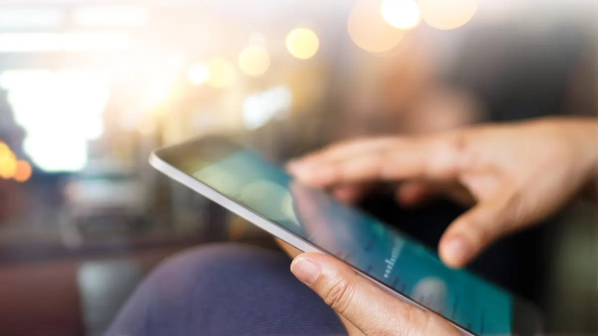 Eine Person hält ein Tablet in der Hand.