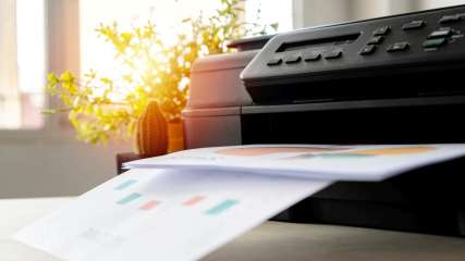 Ein schwarzer Drucker druckt mehrere farbige Dokumente aus.