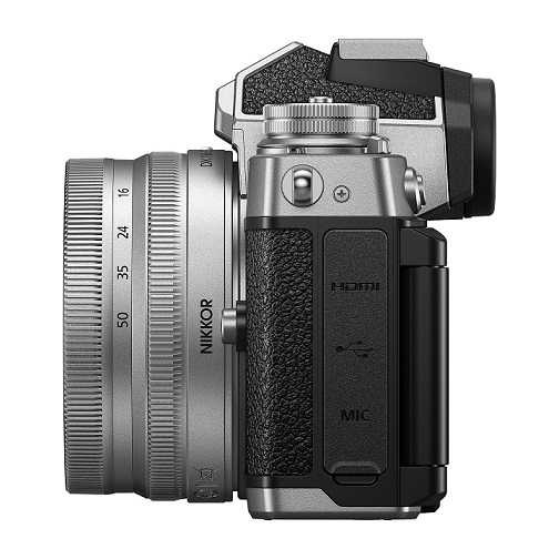 Eine silberne Nikon-Kamera mit schwarzem Griff und einem NIKKOR-Objektiv ist seitlich abgebildet.