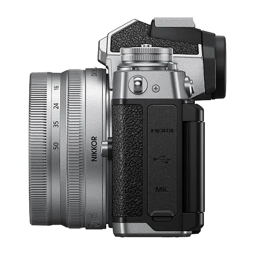 NIKON Z fc Kit Systemkamera mit Objektiv 16-50 mm, 7,5 cm Display Touchscreen, WLAN Eine silberne Nikon-Kamera mit schwarzem Griff und einem NIKKOR-Objektiv ist seitlich abgebildet.