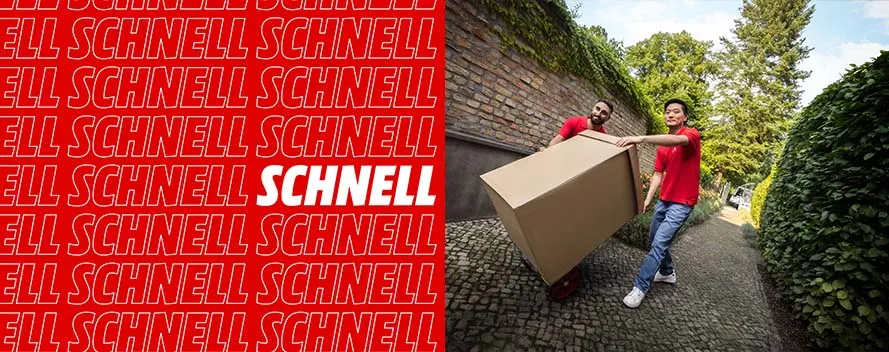 Zwei Personen in roten Hemden transportieren einen großen Karton auf einem Pflasterweg, links roter Hintergrund mit Text.