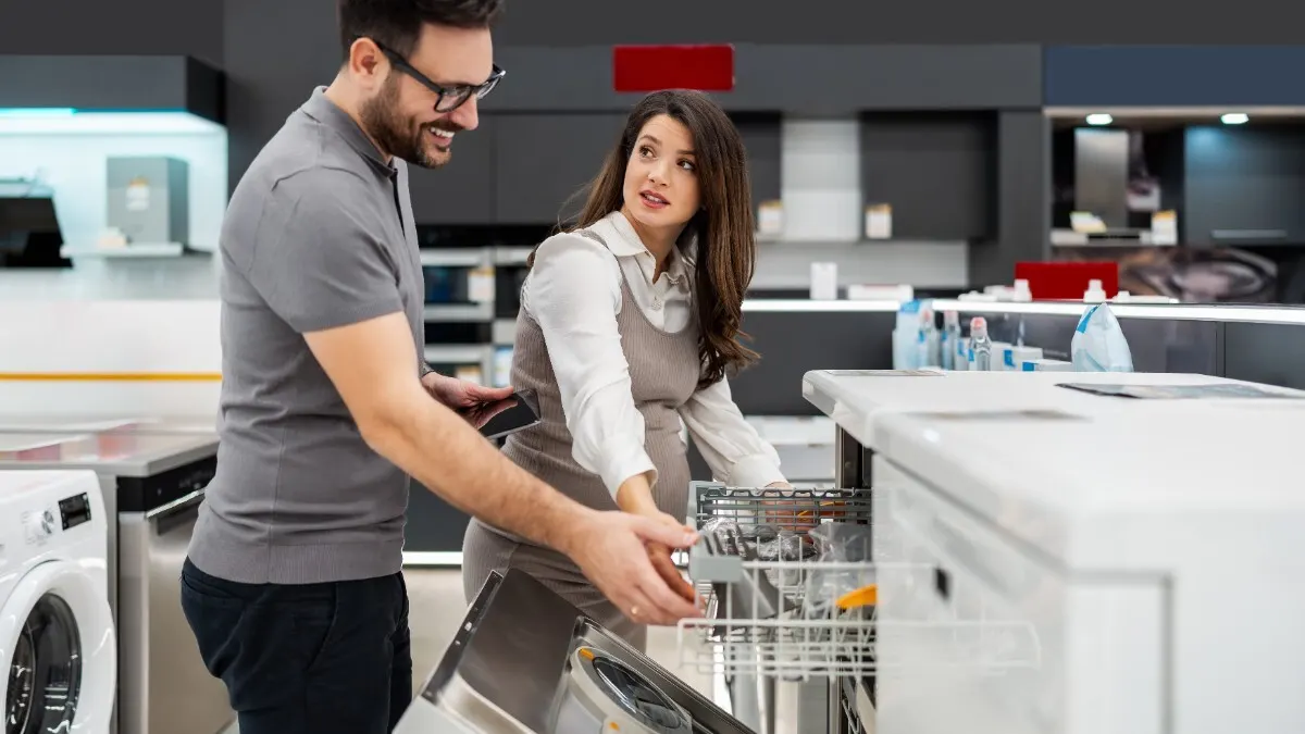 Ein Mann und eine Frau sehen sich Geschirrspüler im Fachhandel an.