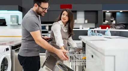 Ein Mann und eine Frau sehen sich Geschirrspüler im Fachhandel an.