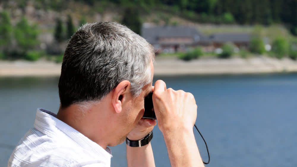Ein Mann fotografiert mit einer Digitalkamera das Meer.