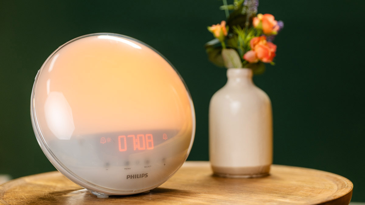Ein Philips-Lichtwecker steht neben einer Blumenvase auf einem Beistelltisch.
