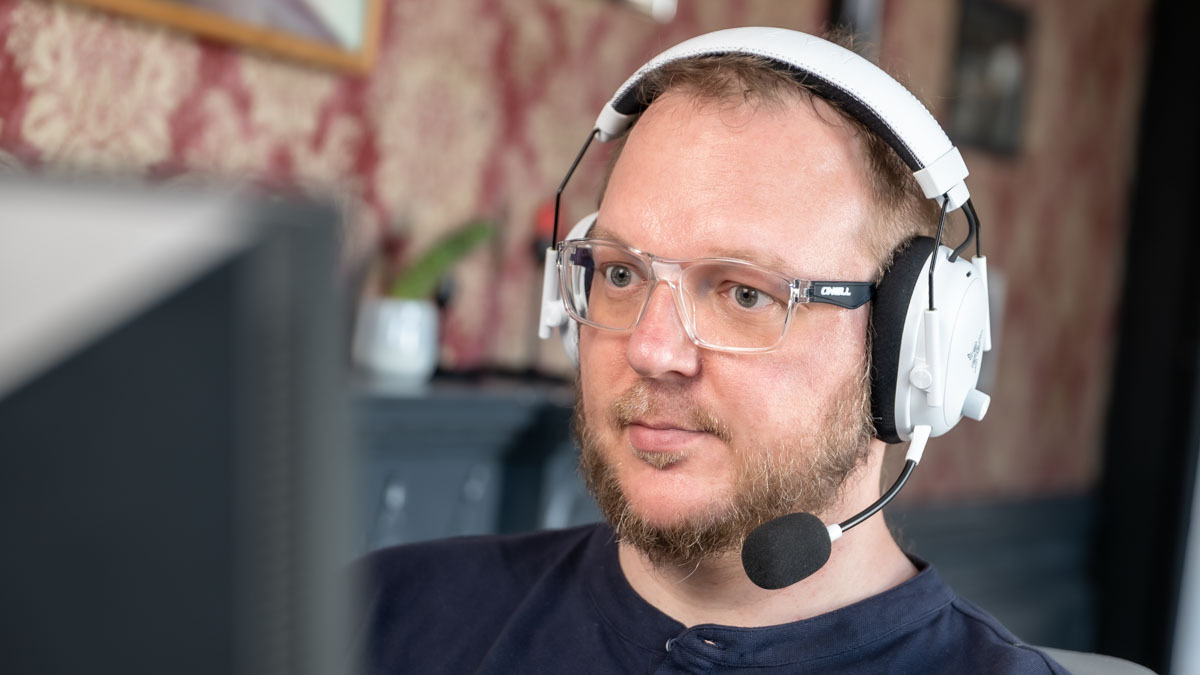 Andreas mit dem Razer BlackShark V3 Pro auf dem Kopf schaut auf einen Monitor.