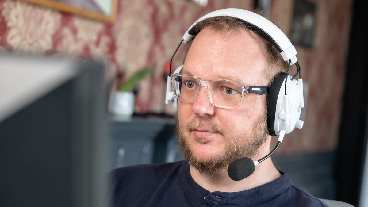 Andreas mit dem Razer BlackShark V3 Pro auf dem Kopf schaut auf einen Monitor.