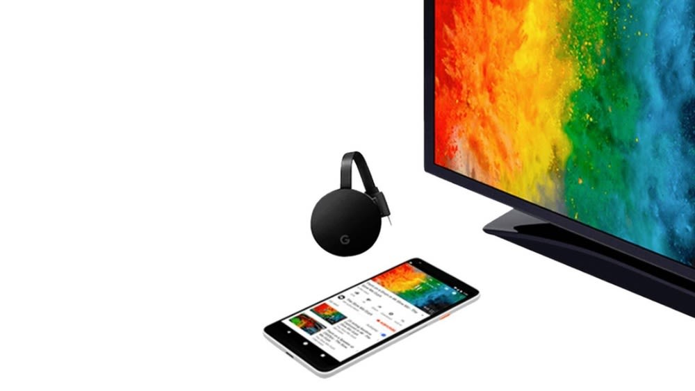 Smartphone liegt neben einem Fernseher und einem schwarzen Google Chromecast