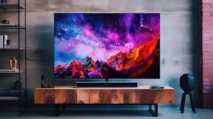 Ein TV-Gerät zeigt eine bunte Landschaft. Der Fernseher steht auf einem Holzschrank mit einer Soundbar. Ein Regal und ein Stuhl sind sichtbar.